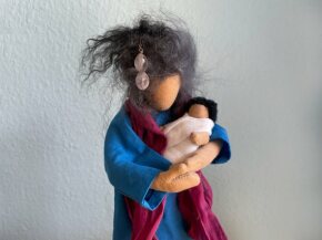 Puppe wiegt kleines Kind in den Armen